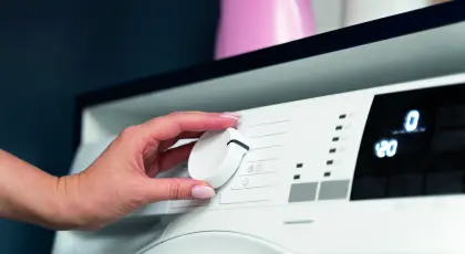 Frau wählt Waschprogramm – mit günstigen Stromtarifen der EV Greiz im Alltag Energie und Kosten sparen